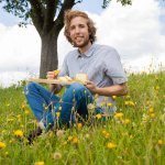 Gerrit Woerle auf Blumenwiese mit Käsebrett - Käserei Woerle