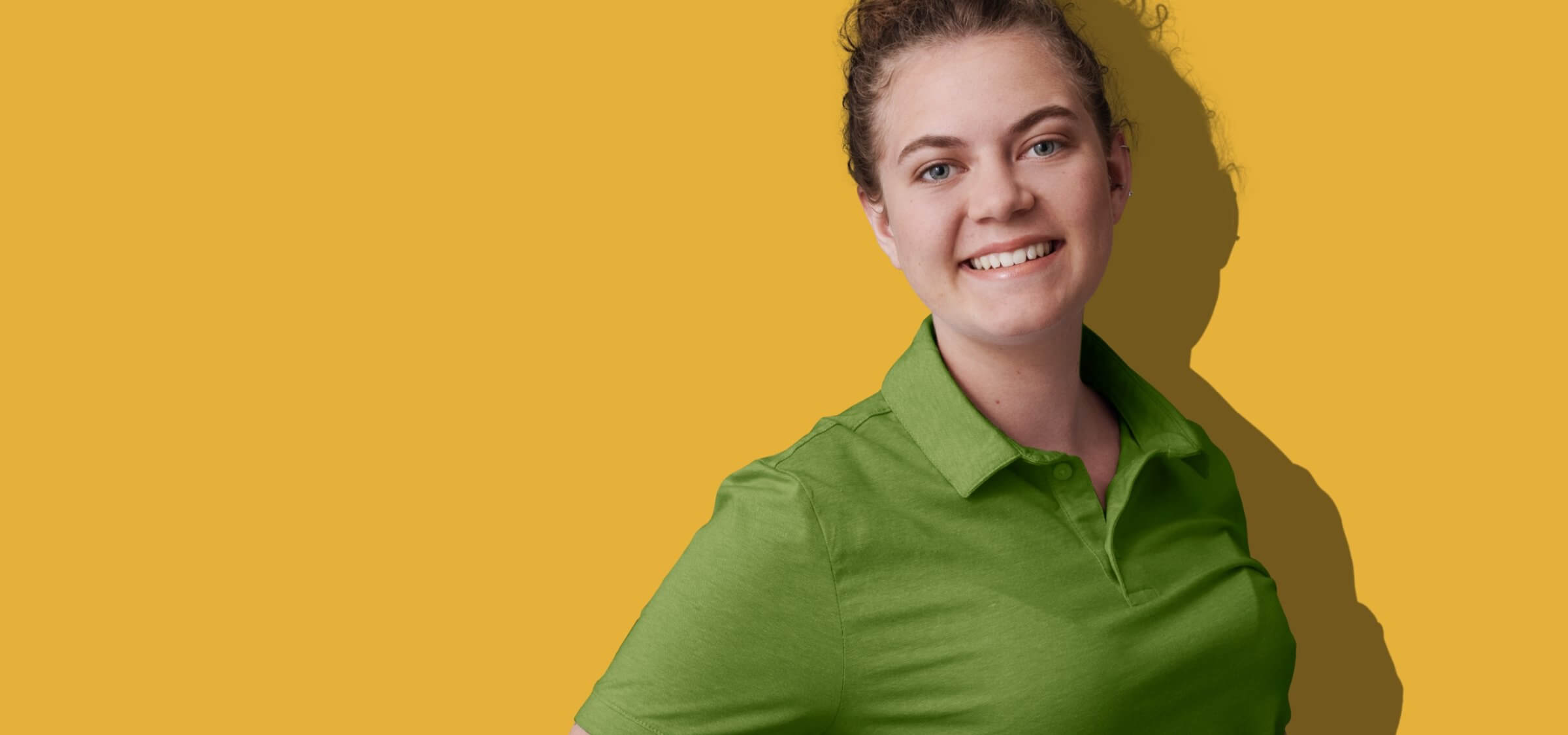 Woerle Lehrling im grünen Poloshirt vor einem gelben Hintergrund