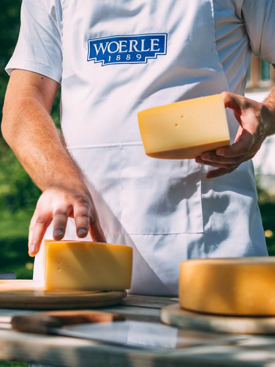 Der runde Käseleib wird von einem Woerle Mitarbeiter geschnitten und präsentiert