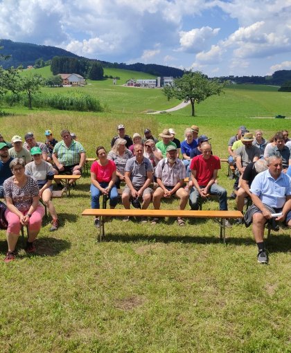 Bauernhofspaziergang mit Leuten, die auf einer Bank sitzen und einem Vortrag lauschen – Käserei Woerle