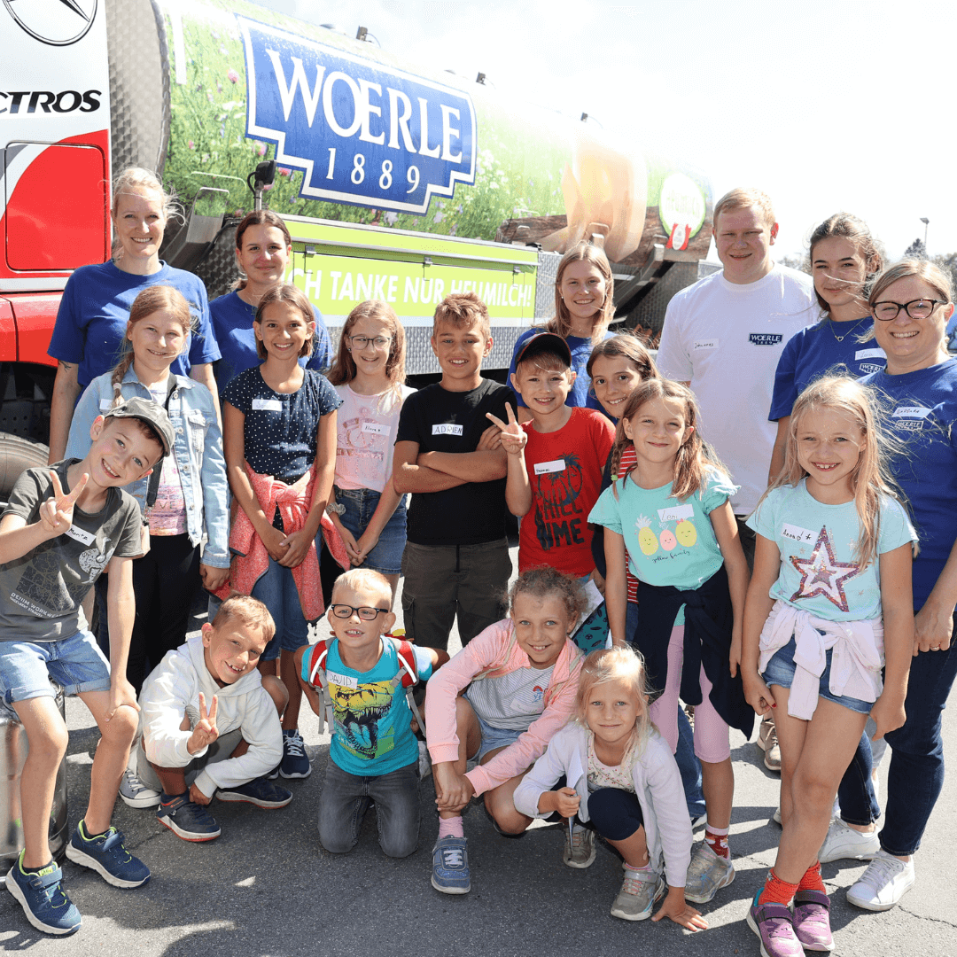 Gruppenfoto von Kindern und Mitarbeitern der Käserei Woerle vor einem LKW mir WOERLE Aufdruck 