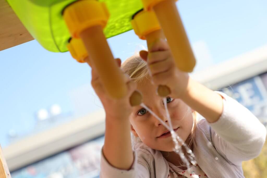Ein Kind melkt eine Melkatrappe. Vor der Käserei WOERLE im Rahmen des Aktionstages in Henndorf
