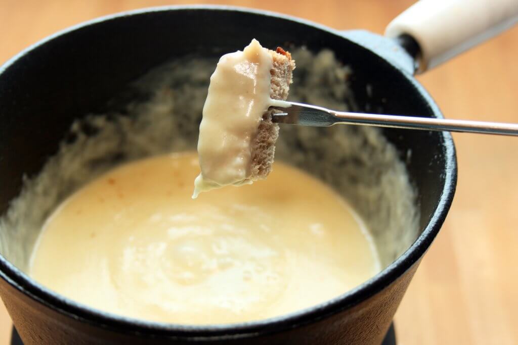 Ein Stück Brot wird mit einem Spieß in geschmolzenen WOERLE Käse getunkt, der in einer Schüssel ist. Er wurde so verwertet.