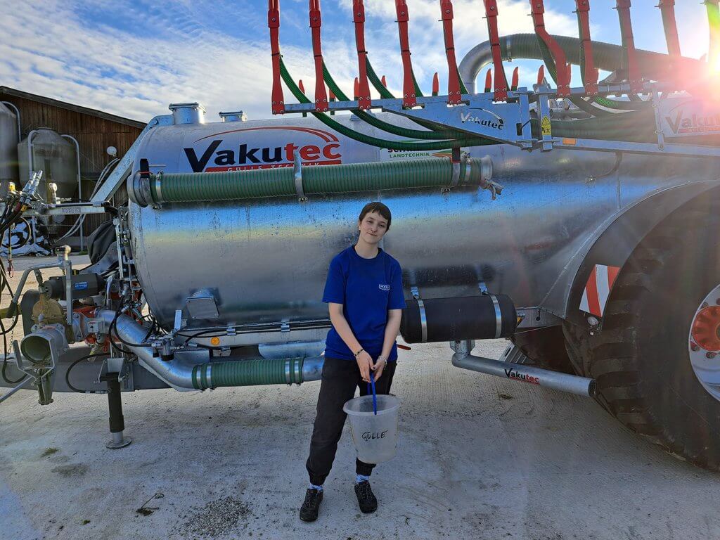 Praktikantin Regina steht vor einem Gülle-Wagen