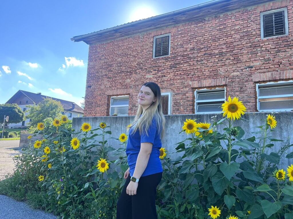 Praktikantin Elena steht vor schönen Blumen