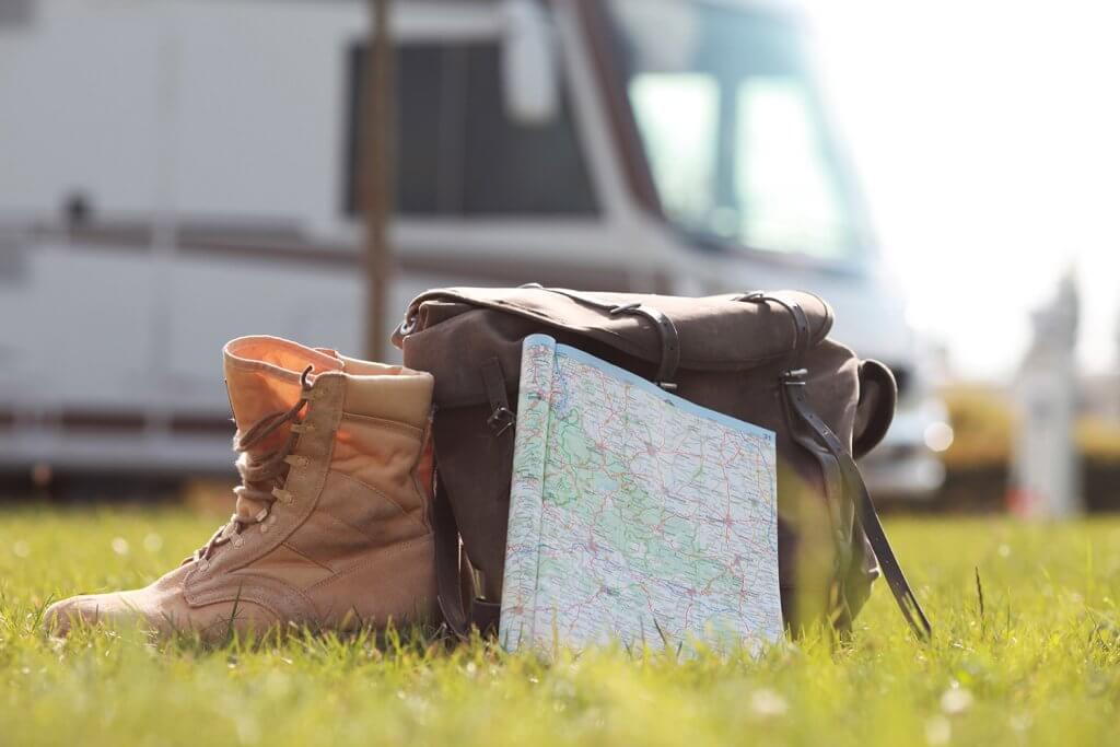Wanderschuh, Wanderrucksack und Wanderkarte vor einem Wohnmobil